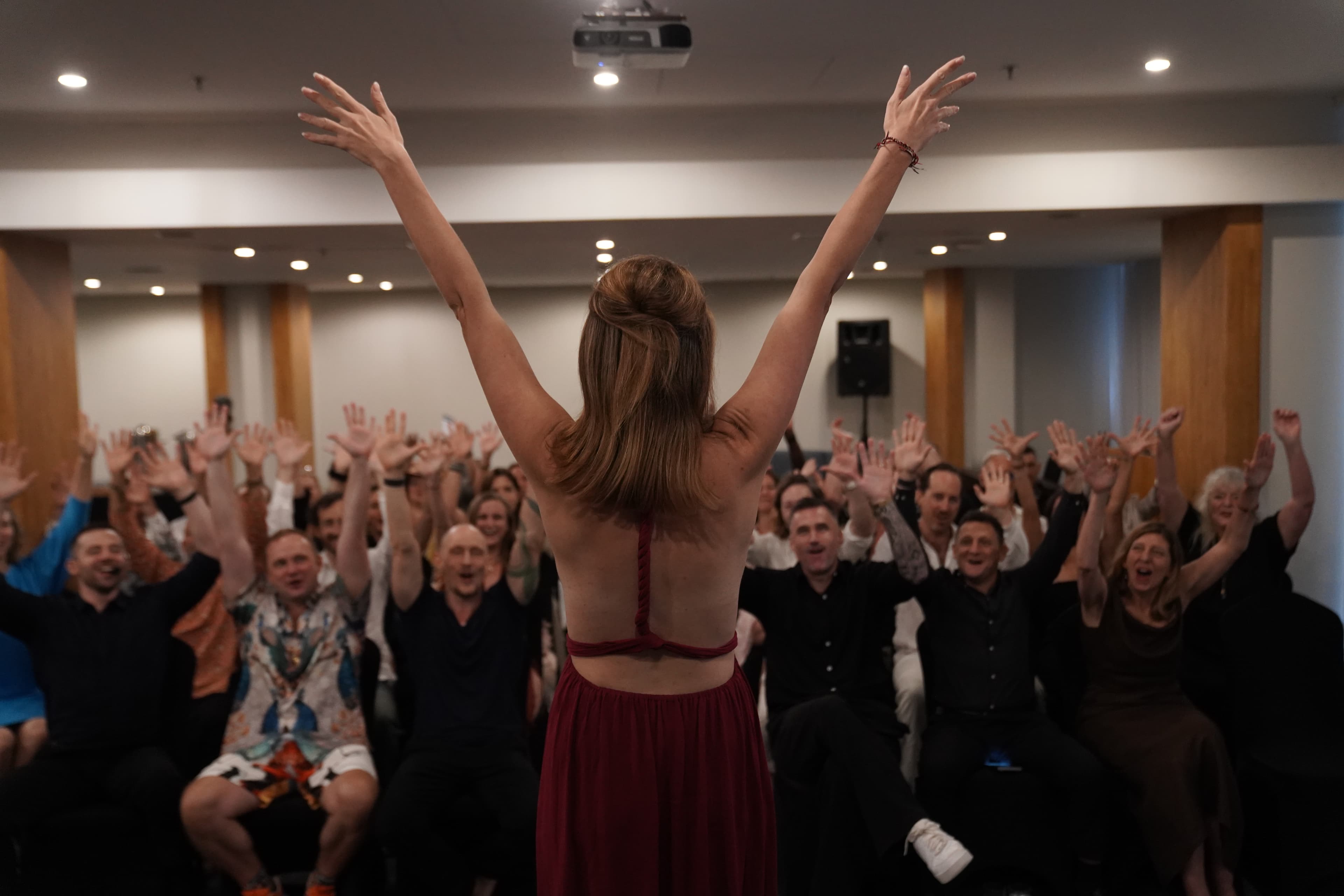 Kirsty Jayne Tait on stage, arms raised, with the audience mirroring her