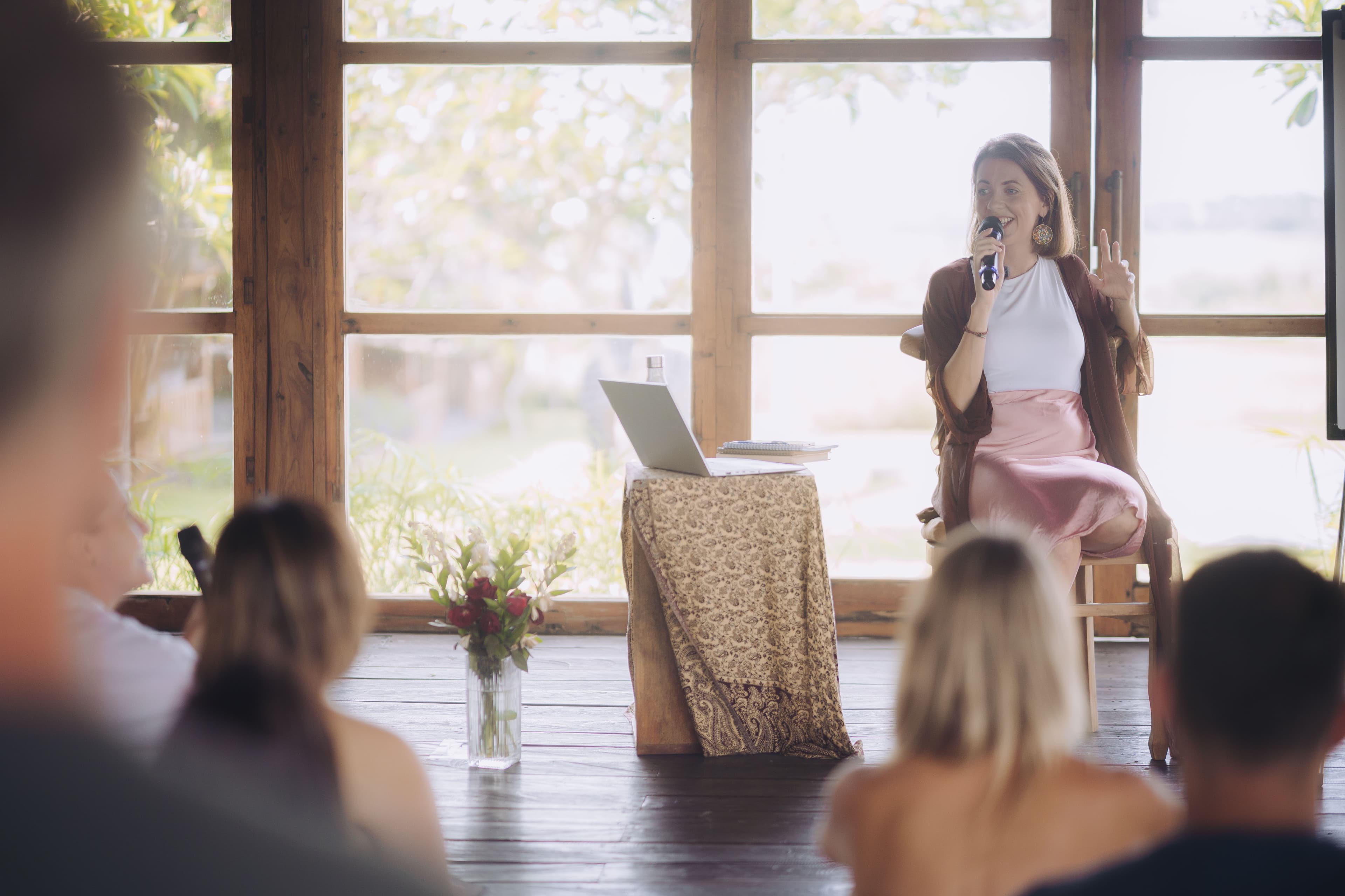 Kirsty speaking to a retreat group, backlit by a window